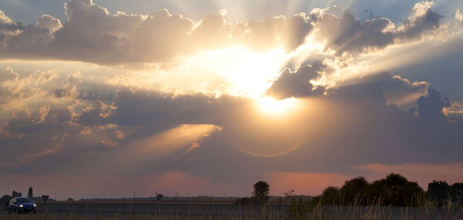Light rays shoot out from behind a thick cover of clouds in the sky.